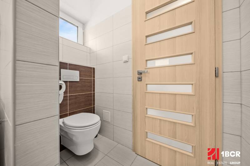 A toilet in a family house with light tiles and doors with vertical stripes.