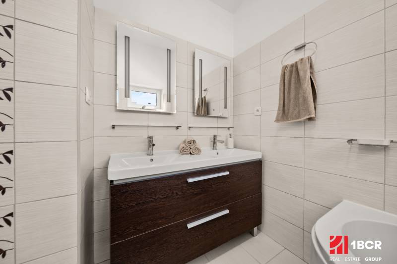A bathroom in a family house with a double sink and a dark cabinet.