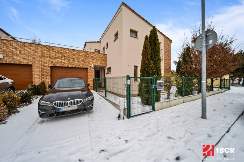 A family house in Konopiská in Bratislava-Čunovo with a brick facade, a snow-covered walkway, and a car.