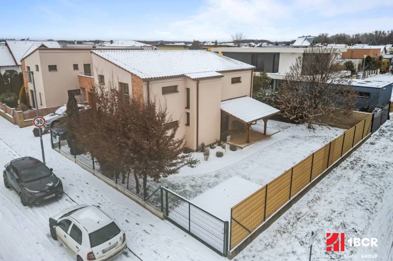 Family house in Bratislava - Čunovo on Konopiská Street, snowy street, parked cars.