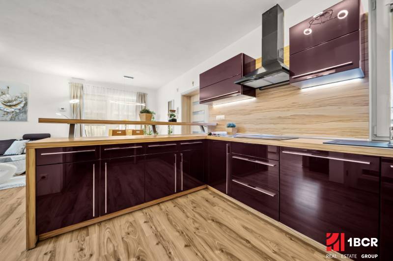 A kitchen in a family house with a wooden decor floor and a glossy kitchen unit.
