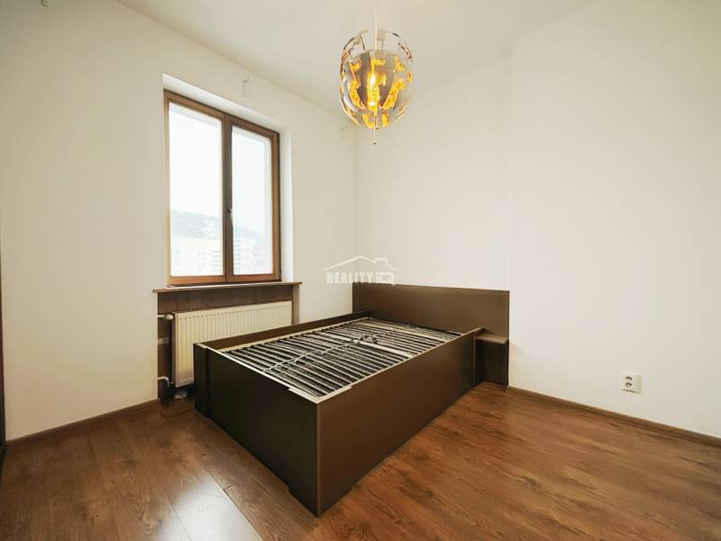 Bedroom in a two-room apartment with a solid wood bed and a floor with a wooden decor.
