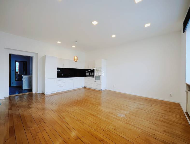 A kitchen in a 2-room apartment with white cabinets and a wood-patterned floor.