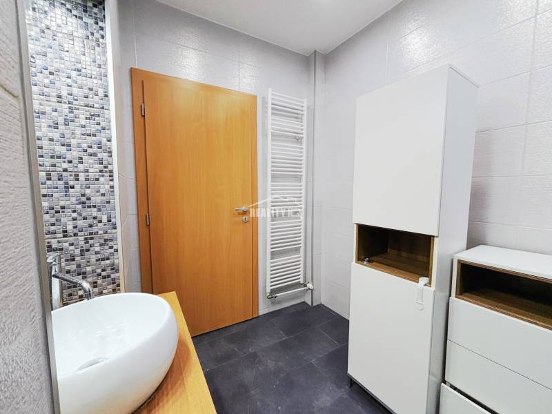 Bathroom with a sink, white cabinets, and mosaic tiles in a 2-room apartment.