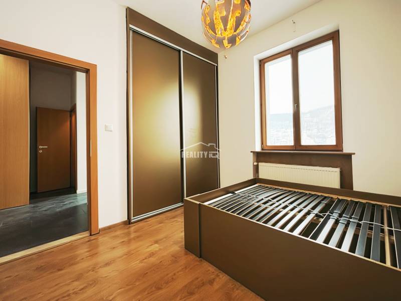 A bedroom in a two-room apartment with a wood-patterned floor, a large wardrobe, and a radiator.