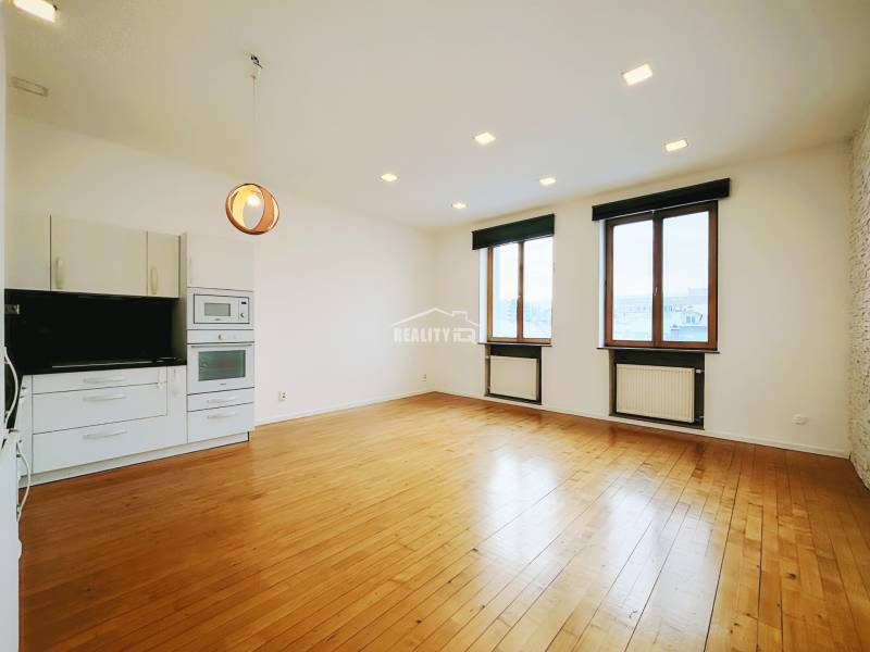 Living area in a 2-room apartment with a kitchen unit and a wooden decor floor.