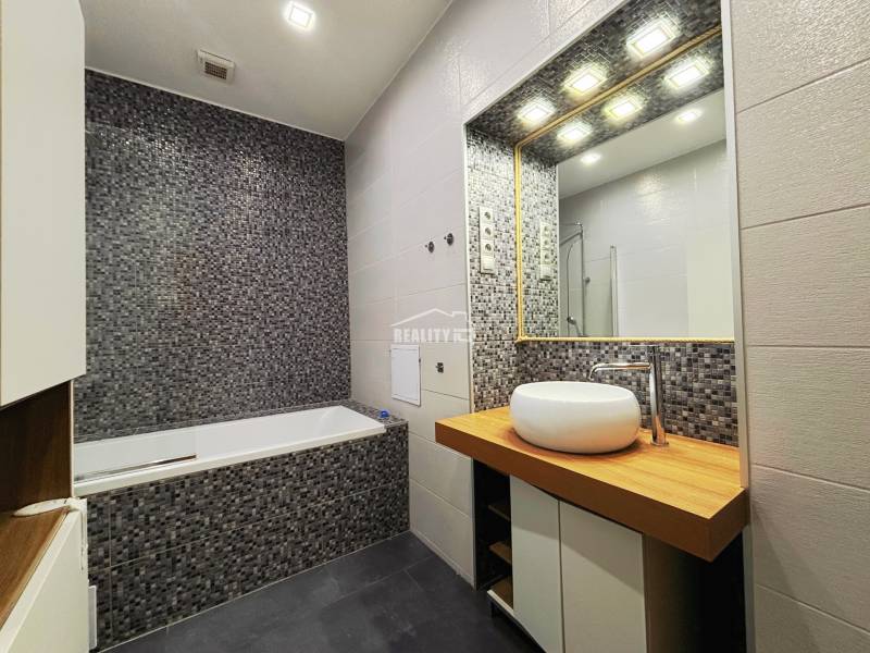 Bathroom in a 2-room apartment with mosaic tiles, a sink, and a bathtub.