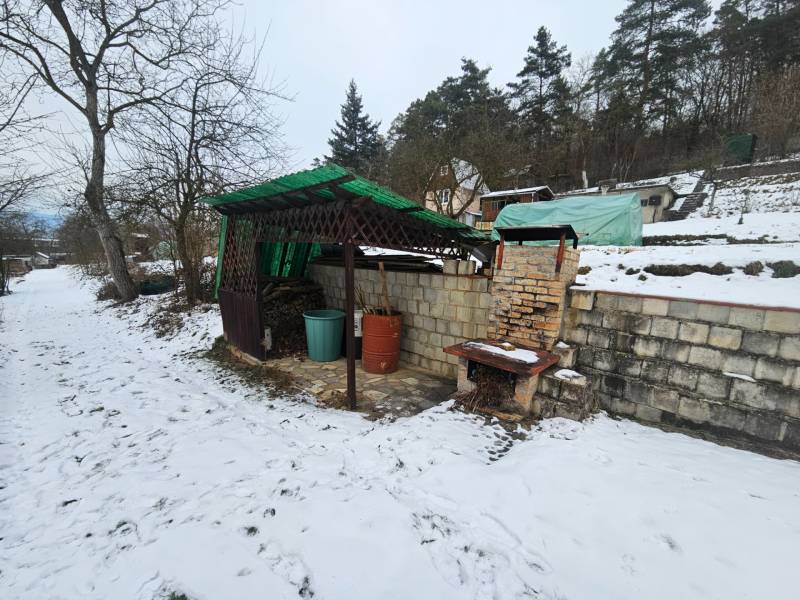 Winter scene in Lieskovec, Dubnica nad Váhom with a cottage, shelter, and brick grill.