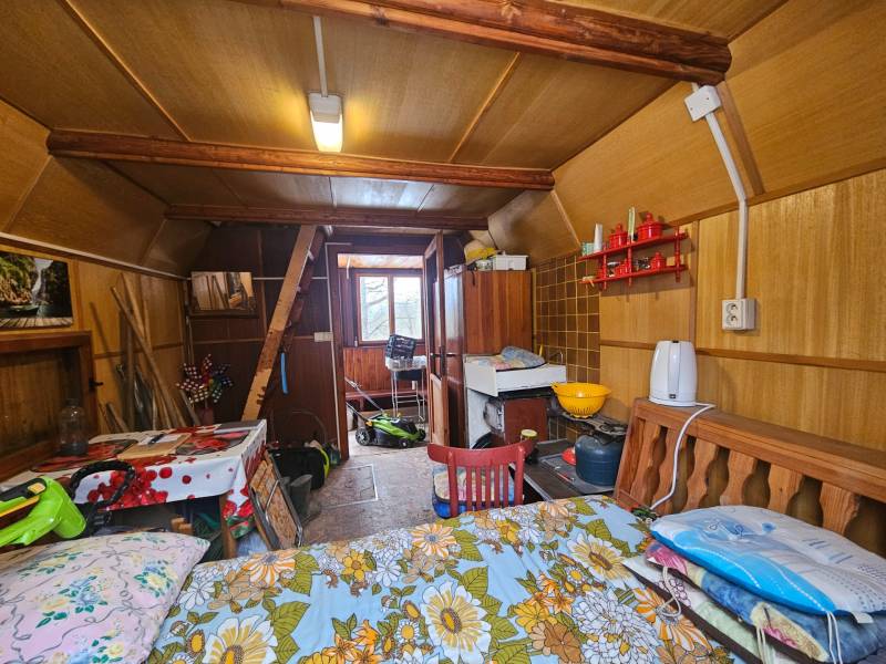 Interior of a cabin with wooden decor, furniture, and kitchen utensils.