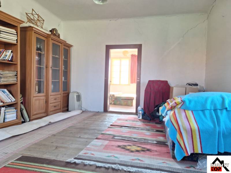 A room in a family house with bookshelves, a bed with a colorful blanket, and a carpet.