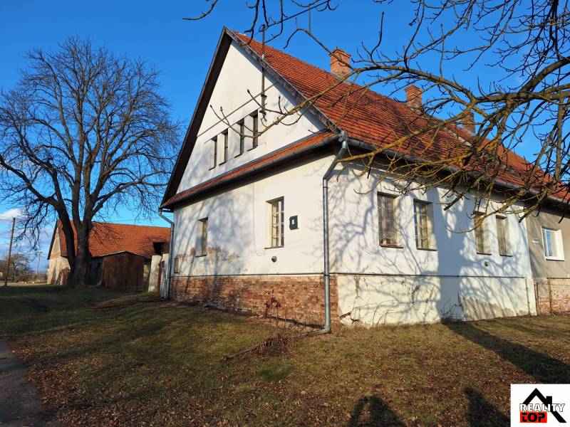 A family house in Orávka with a large garden and a nearby tree in the winter season.