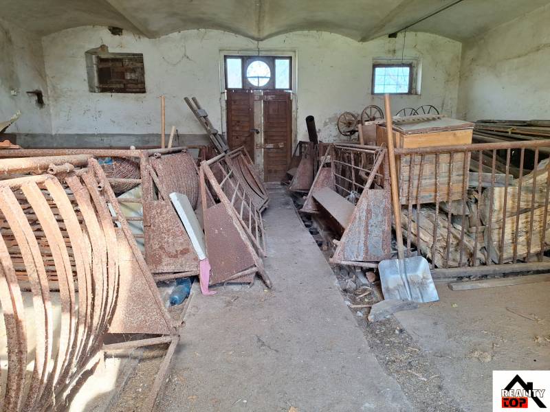 An old barn in a family house with rusty metal equipment and wood on the floor.