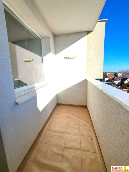 The balcony of a 4-room apartment, overlooking the rooftops and a clear sky.