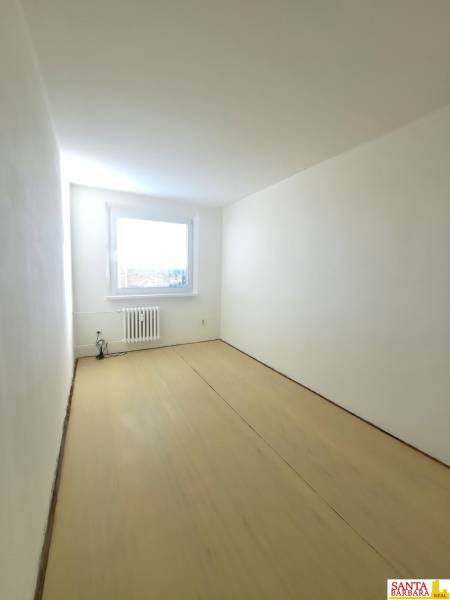 A room in a 4-room apartment with white walls and a wooden decor floor.