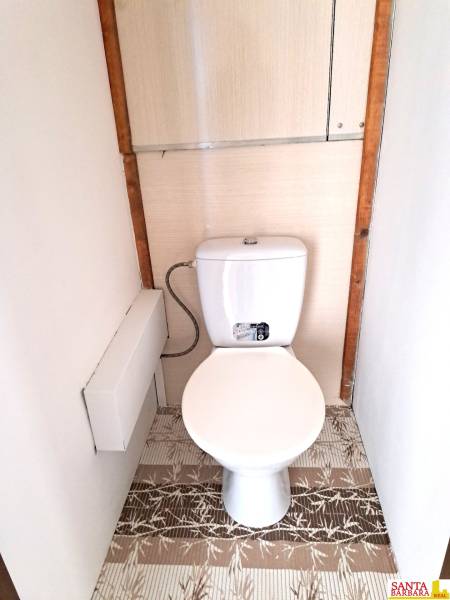A toilet with a white flush and a floor with a wooden decor in a 4-room apartment.