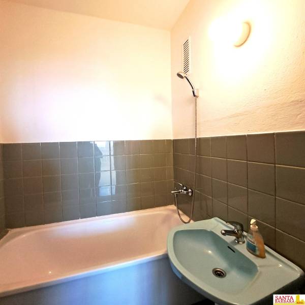 A bathroom with green tiles, a bathtub, and a sink in a 4-room apartment.