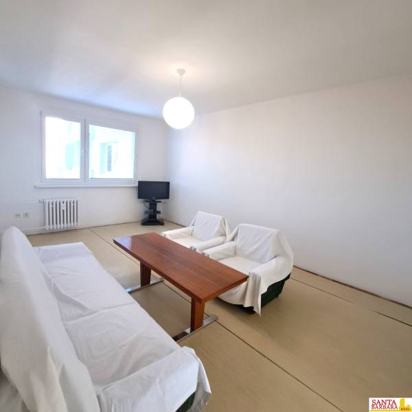Living room with a table and a sofa in a 4-room apartment, floor with wood decor.