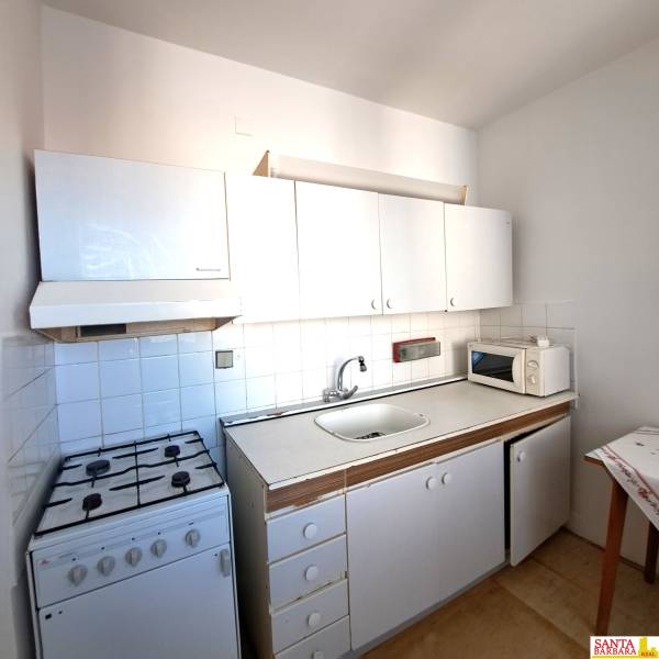 A kitchen in a 4-room apartment with a stove, white cabinets, and a microwave.