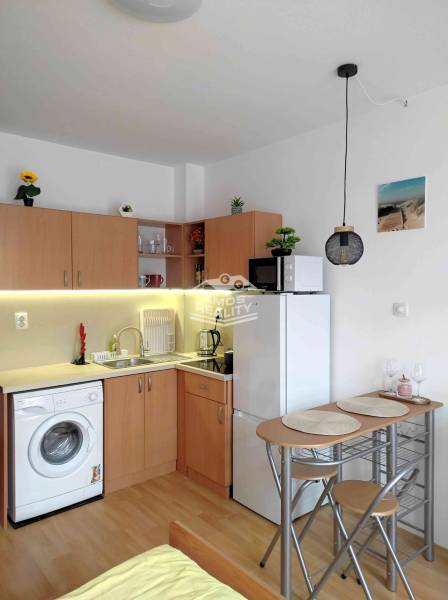 Kitchen corner in a holiday apartment with a washing machine, refrigerator, and table.