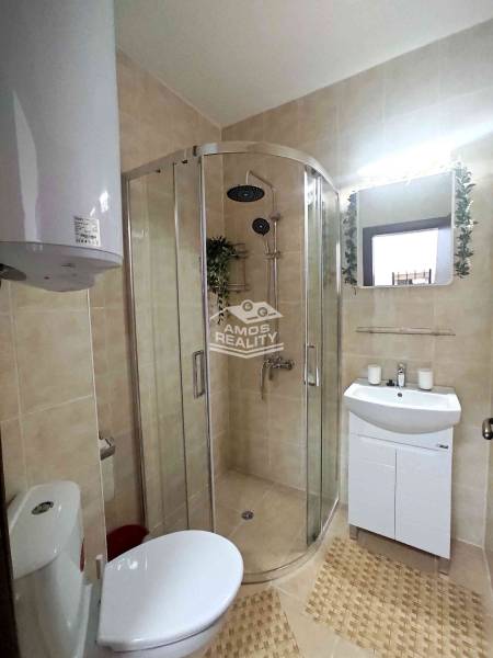 A bathroom in a holiday apartment with a corner shower, sink, and mirror in a decorative frame.