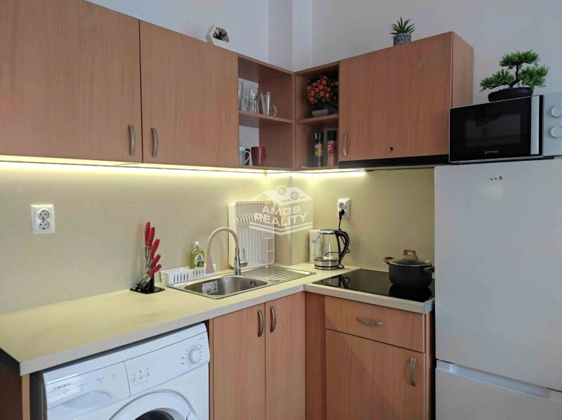A kitchen in a holiday apartment with wooden decor, appliances, and a sink.