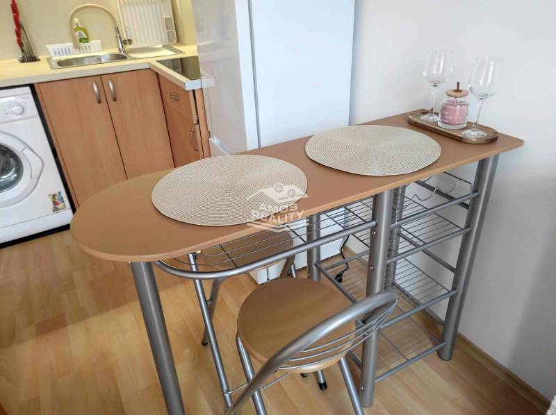 Kitchen corner of the holiday apartment with a bar table, stools, and a floor with a wooden decor.