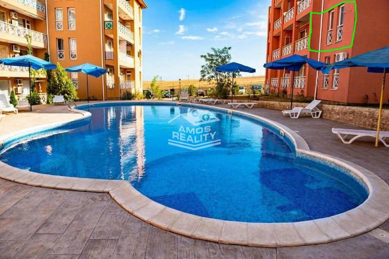 A holiday apartment in Burgas with a swimming pool, sun loungers, and umbrellas on a paved terrace.