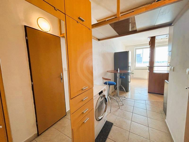 Entrance hall of a 2-room apartment with tiles and an equipped kitchenette.