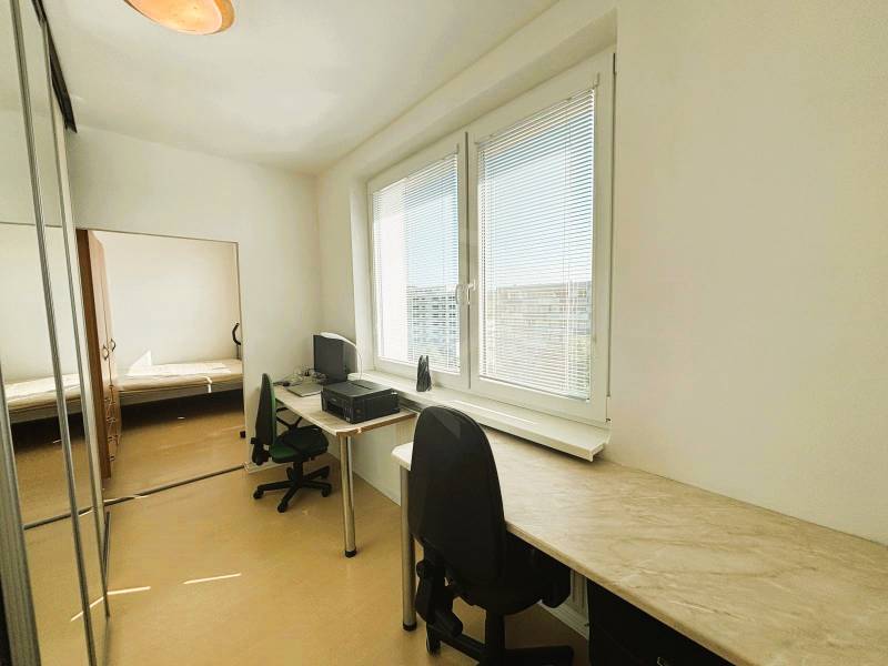 A study with a desk and a chair, a floor with a wooden decor, large windows, a 2-room apartment.