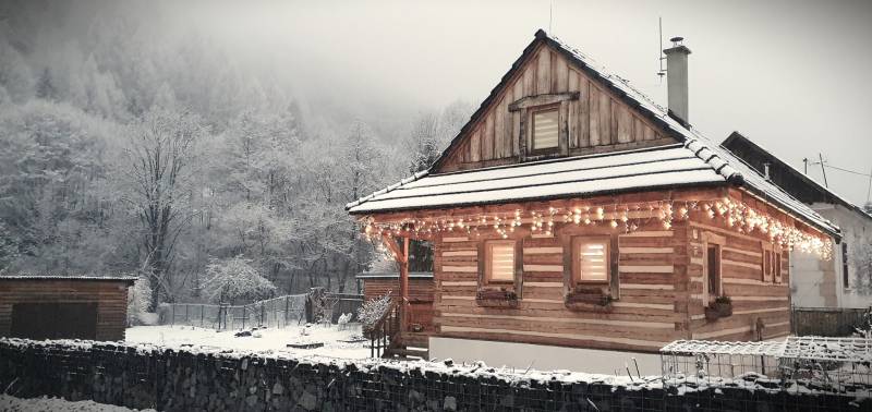 A snow-covered cottage on Hviezdoslav Street in Tisovec with winter decorations.