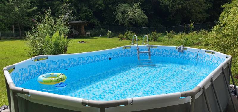 An inflatable pool in the garden of a cottage, surrounded by greenery on Hviezdoslavova Street in Tisovec.