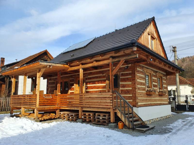 A wooden cottage on Hviezdoslavova Street in Tisovec covered with snow and solar panels.