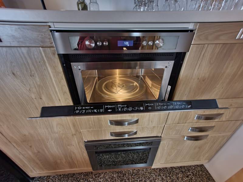 Microwave oven in a room with wooden floor decor and kitchen unit.