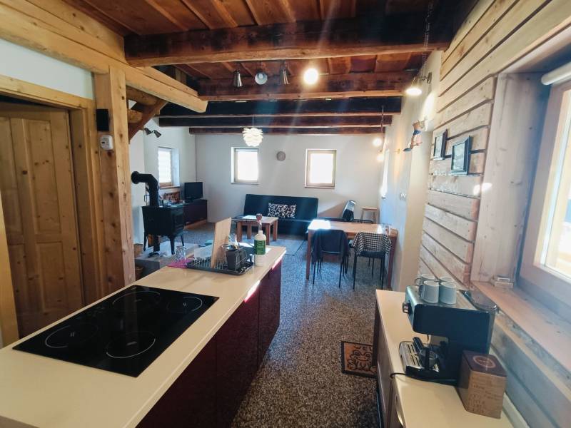 A cottage with wooden elements and tiles, a floor with a wooden decor, a kitchen island.