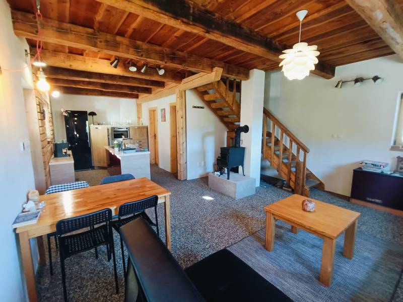 The interior of a cabin with a wooden decor floor, wooden ceiling, and a tiled stove.