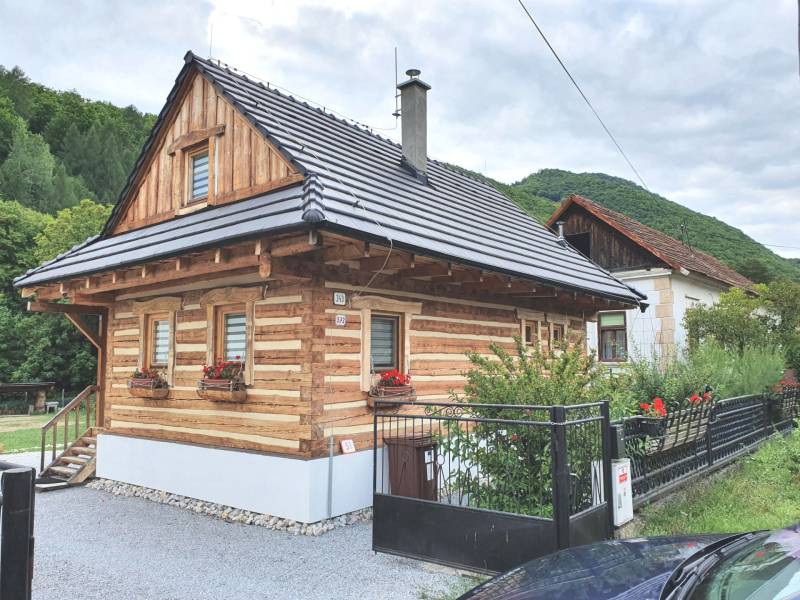 Wooden cottage on Hviezdoslavova Street in Tisovec surrounded by green hills.