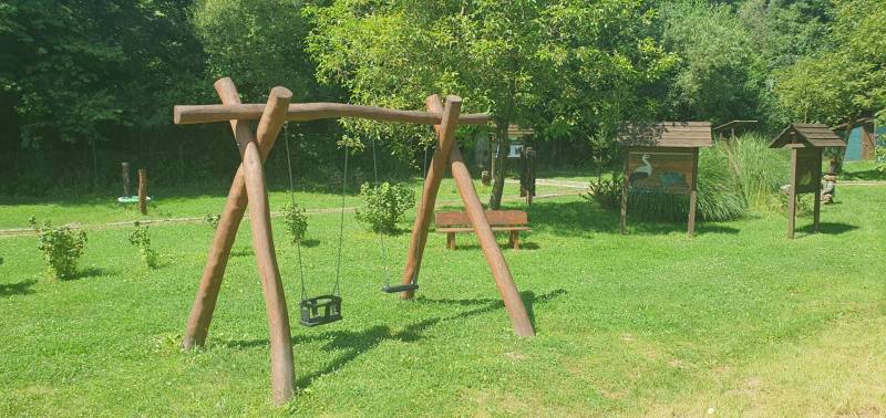 Wooden swings in the park on Hviezdoslavova Street in Tisovec surrounded by greenery.