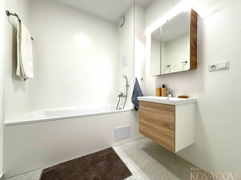 A bathroom in a 3-room apartment with a bathtub and furniture with a wooden decor.