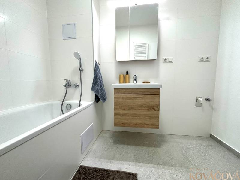 Bathroom in a 3-room apartment with a bathtub, mirror cabinet, and white tiles.