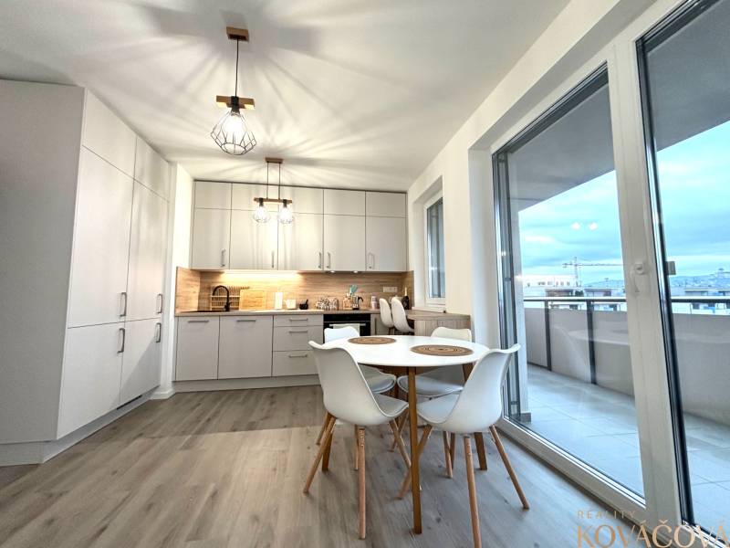 A kitchen in a 3-room apartment with a wooden decor floor and a balcony.