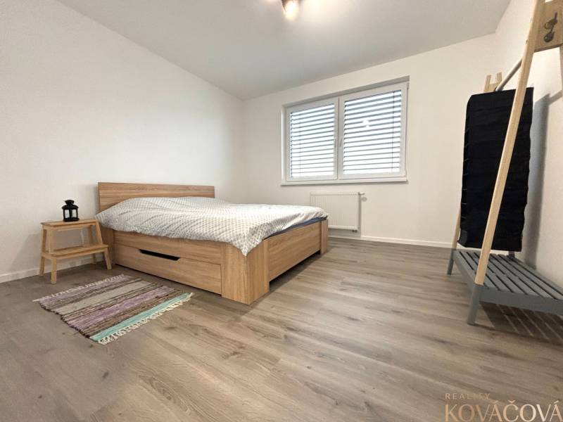 Bedroom in a 3-room apartment with a bed, wooden decor flooring, and simple furniture.