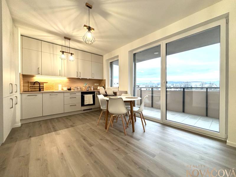 Kitchen in a 3-room apartment with a dining table, wood-patterned floor, balcony doors.