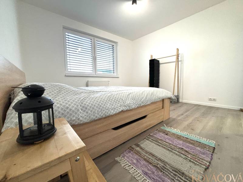 Bedroom in a 3-room apartment with wood-patterned flooring, a bed, and a nightstand.