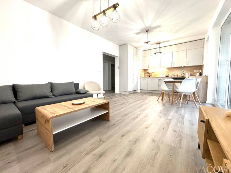 Living room with kitchen in a 3-room apartment, wooden decor flooring, bright interior.
