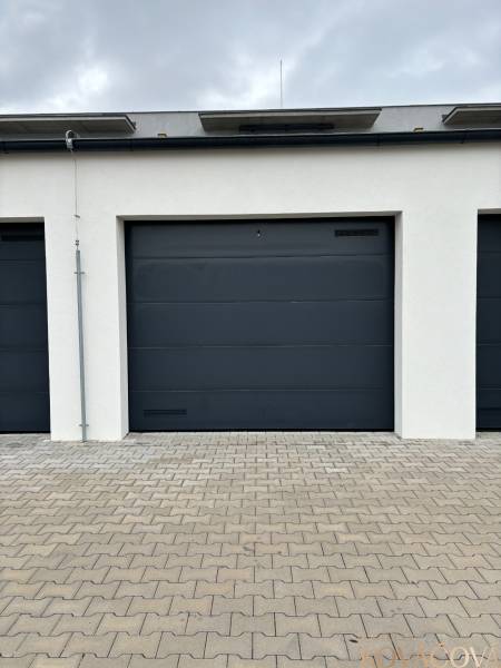 A garage with gray doors on a paved area on Vladimíra Predmerského Street in Trenčín.