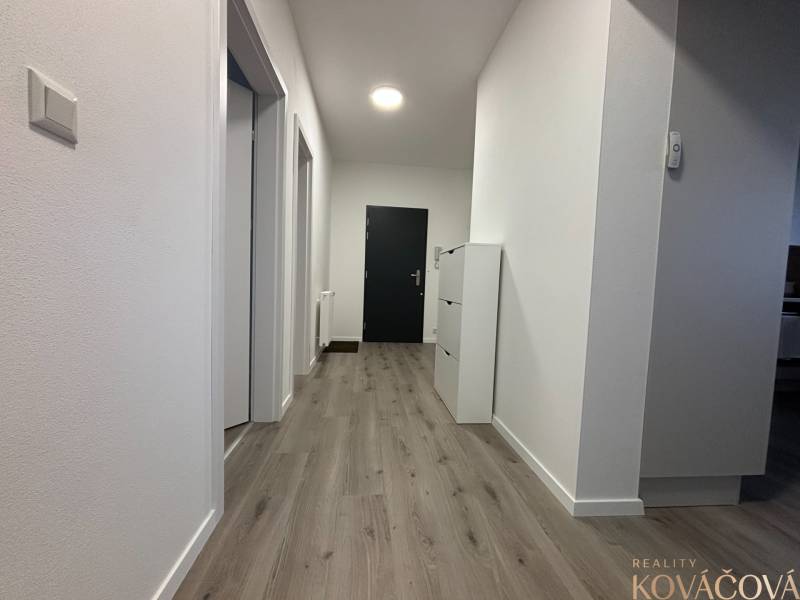 A hallway in a 3-room apartment with a wooden decor floor and white walls.