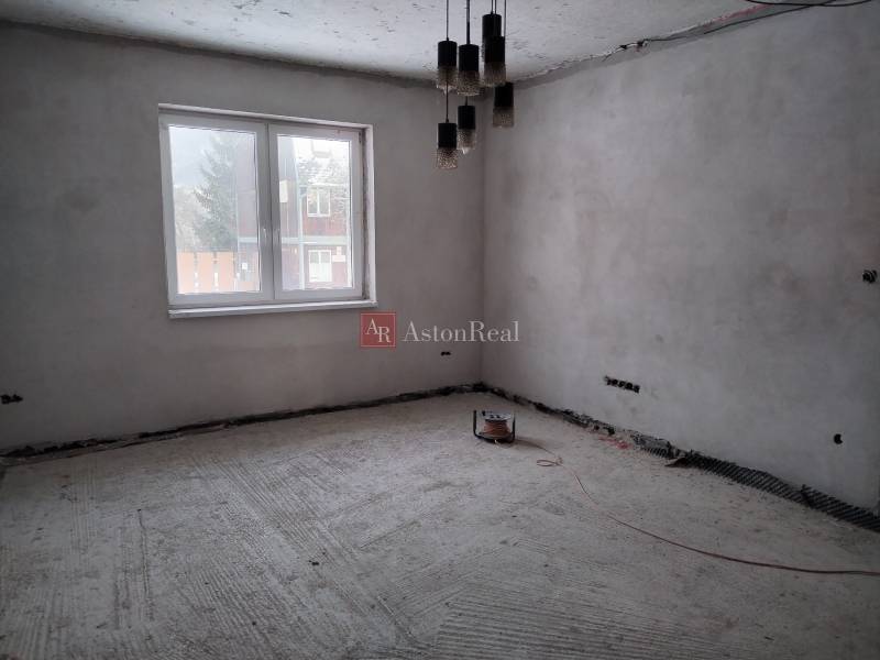 Unfinished room with a concrete floor, large window, and hanging lights in a family house.