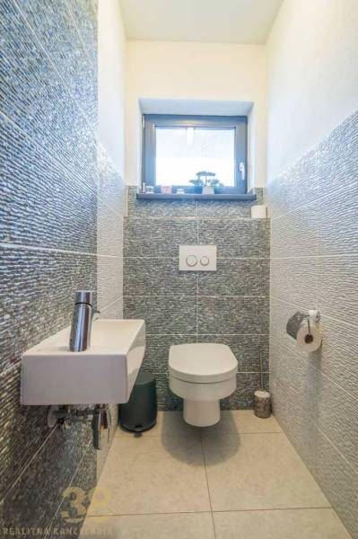 A bathroom in a family house with a sink, toilet, and cozy tiling.