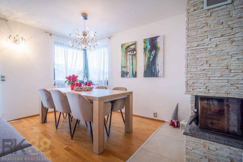 Dining room in a family house with a wood-patterned floor, a fireplace, and wall art.