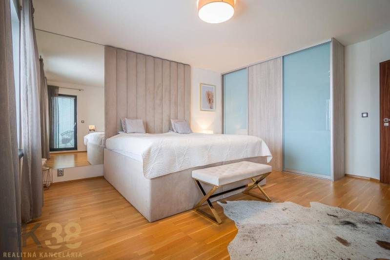 Bedroom in a family house with a bed, wooden decor flooring, and a faux fur rug.
